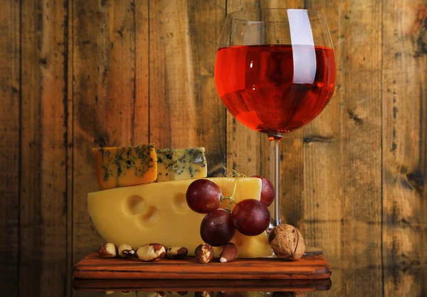 Vino rosa, uvas y queso sobre fondo de madera — Foto de Stock
