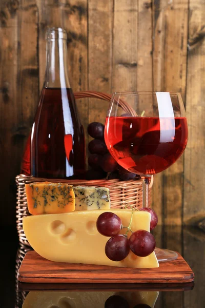 Vin rose, raisins et fromage sur fond de bois — Photo
