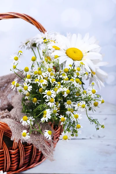 Beautiful bouquet of daisies in wicker basket on wooden background — Stock Photo, Image