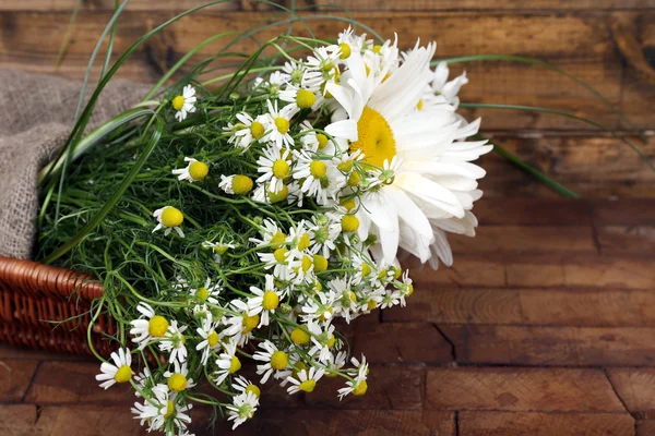 Beautiful bouquet of daisies in wicker basket on wooden background — Stock Photo, Image