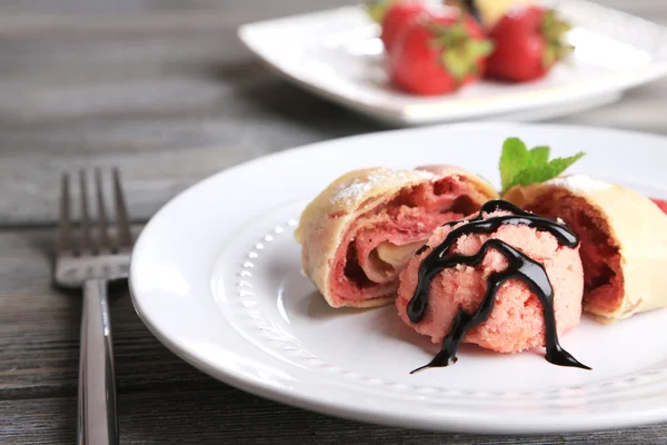 Tasty homemade strudel with ice-cream, fresh strawberry and mint leaves on plate, on wooden background — Stock Photo, Image