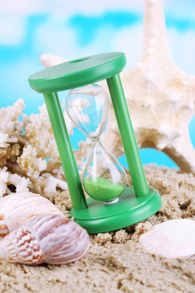 Hourglass in sand on bright background — Stock Photo, Image