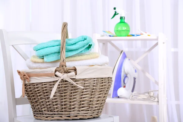 Colorful towels in basket on chair, on home interior background — Stock Photo, Image