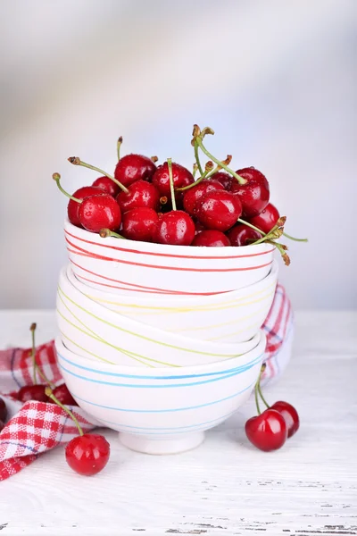 Спелые сладкие вишни в миске на деревянном столе — стоковое фото