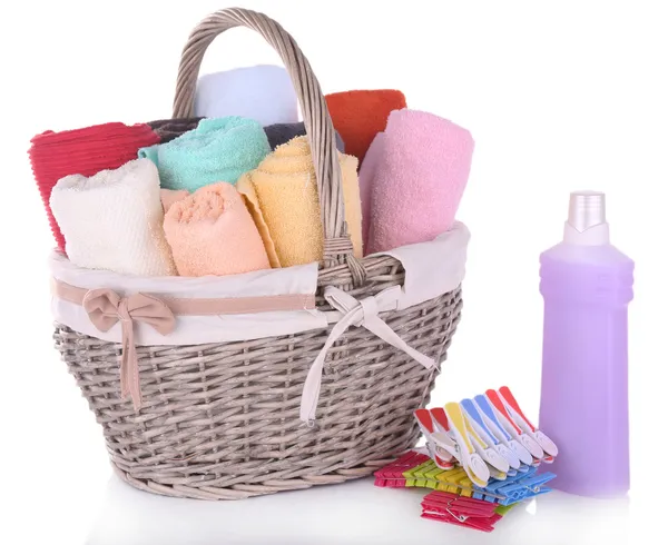 Colorful towels in basket, pins and liquid for washing, isolated on white — Stock Photo, Image