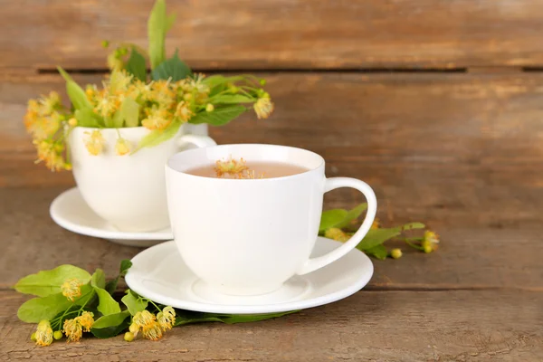 Sabroso té de hierbas con flores de tilo en la mesa de madera —  Fotos de Stock