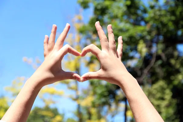 Junges Mädchen hält Hände in Herzform Rahmen auf Natur Hintergrund — Stockfoto