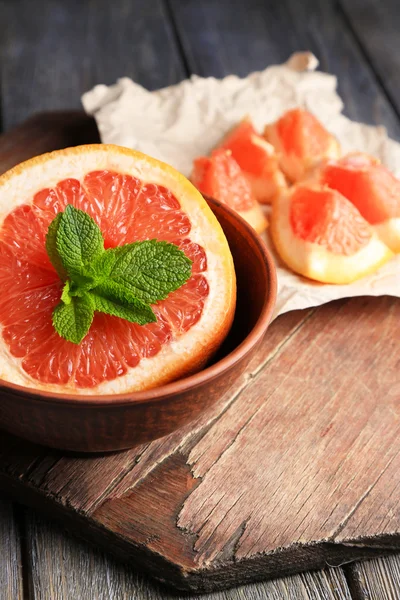 Součástí zralých grapefruitů v míse, na dřevěné pozadí — Stock fotografie