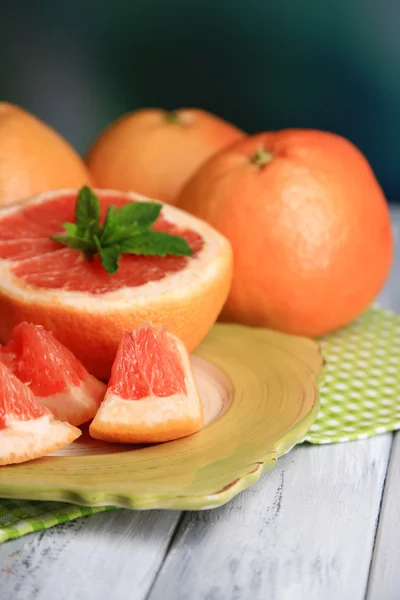 Ripe grapefruits on plate on color wooden background — Stock Photo, Image