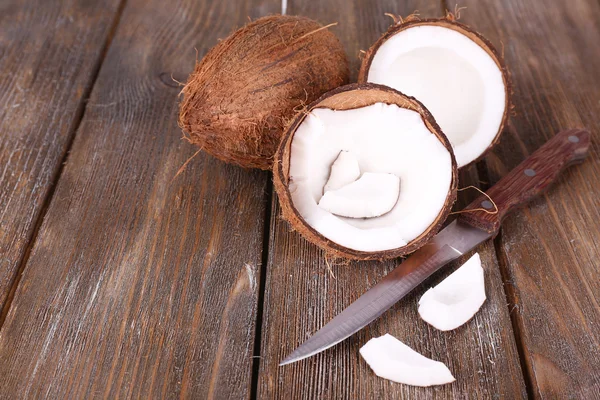 Сломанный кокос с ножом на деревянном фоне — стоковое фото