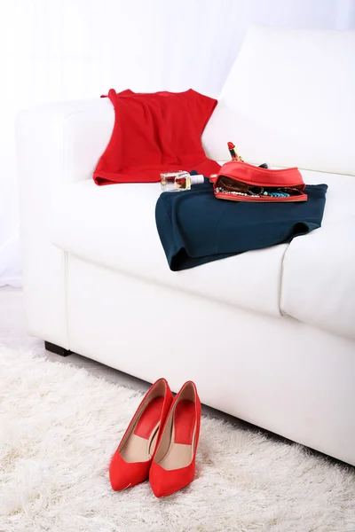Kozmetik çantası, moda giyim, açık renkli kanepe üzerinde parfüm şişesi — Stok fotoğraf