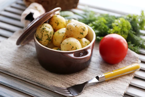 As batatas fervidas jovens na panela na mesa de madeira — Fotografia de Stock