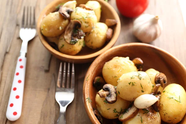 Jonge gekookte aardappelen in kom op houten tafel, close-up — Stockfoto