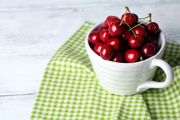 Cerises douces en tasse sur fond en bois — Photo