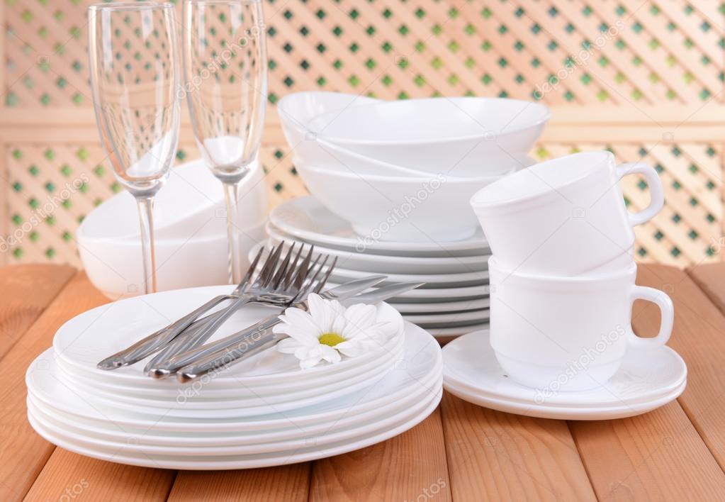 Set of white dishes on table on light background