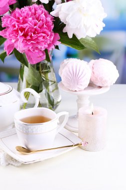 Cam vazo içinde sunulan güzel peonies, çay Kupası ve hatmi, masada açık renkli üzerinde kompozisyon