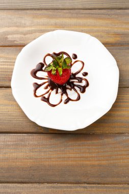 ahşap masa üstünde çikolata ile kırmızı olgun çilek