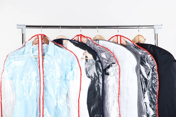 Office female clothes in cases for storing on hangers, on gray background — Stock Photo, Image