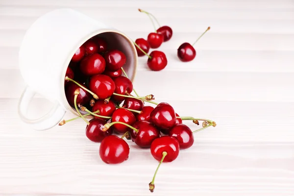 Ripe sweet cherries in cup on wooden table — Stock Photo, Image