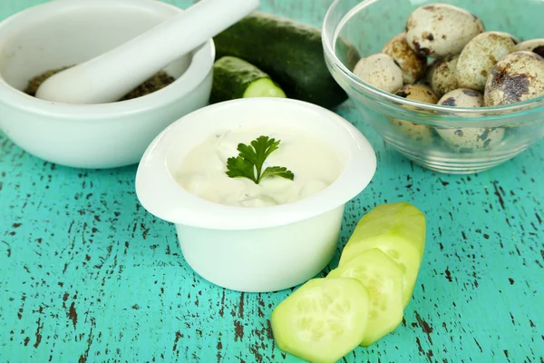 Komkommer yoghurt in kom, op kleur servet, op houten achtergrond — Stockfoto
