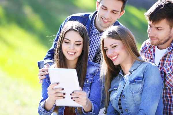 Felices estudiantes sentados en el parque — Stockfoto