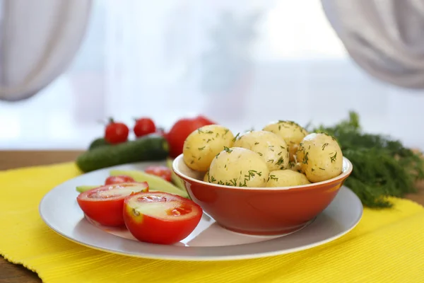 Mladí vařené brambory na tabulce na pozadí okna — Stock fotografie