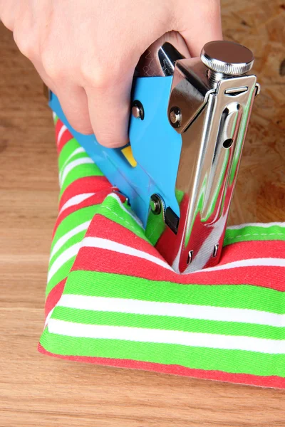 Fastening fabric and board using construction stapler — Stock Photo, Image