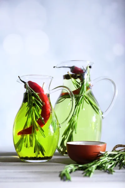 Olio essenziale con rosmarino in brocca di vetro, su fondo chiaro — Foto Stock