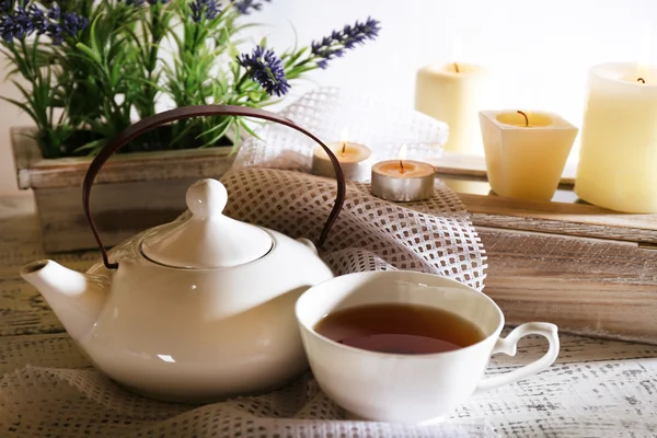 Komposition mit Tee in Tasse und Teekanne und Kerzen auf dem Tisch, auf hellem Hintergrund — Stockfoto
