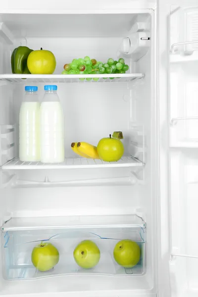 Mjölkflaskor, grönsaker och frukter i öppna kylskåpet. vikt förlust kost koncept. — Stockfoto