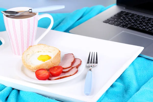 Composition with laptop and tasty breakfast on wooden tray, close-up, on bright background — Stock Photo, Image