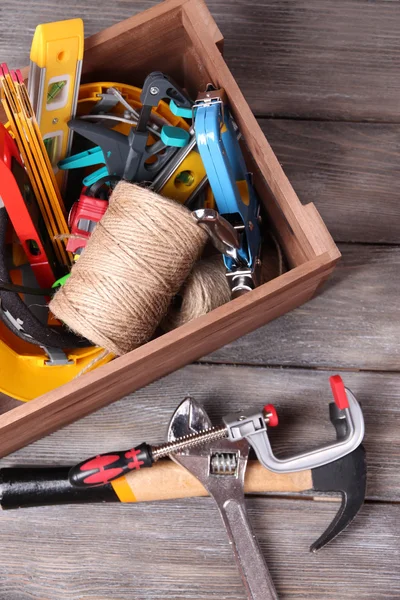 Wooden box with different tools, on wooden background — Stock Photo, Image