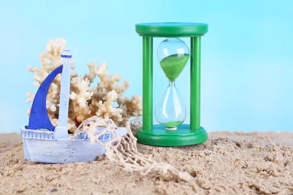 Hourglass in sand on blue sky background — Stock Photo, Image