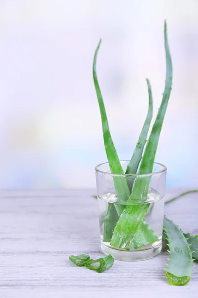 Fresh green aloe leaves in glass on wooden table — Stock Photo, Image