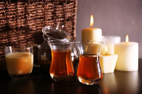 Composition avec thé dans une théière en verre et bougies sur la table, sur fond sombre — Photo