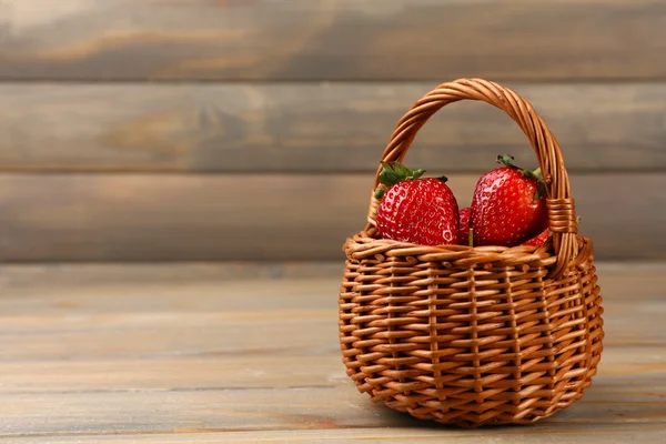 木製の背景に枝編み細工品バスケットで赤い熟したイチゴ — ストック写真