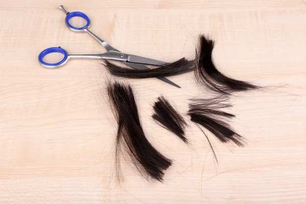 Cut hair and scissors on wooden background — Stock Photo, Image