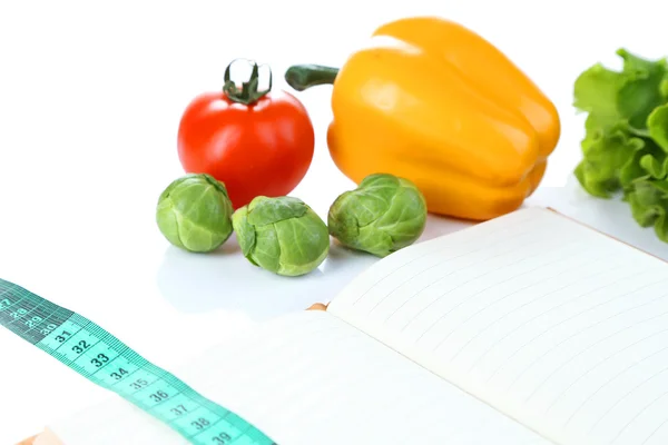 Book with measuring tape and vegetables isolated on white — Stock Photo, Image