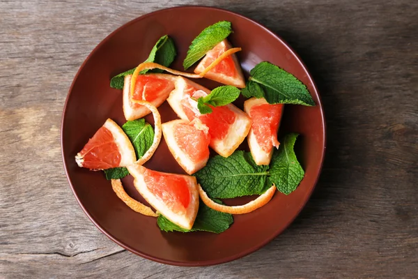 Mogna hackade grapefrukt med mynta blad på plattan, på trä bakgrund — Stockfoto