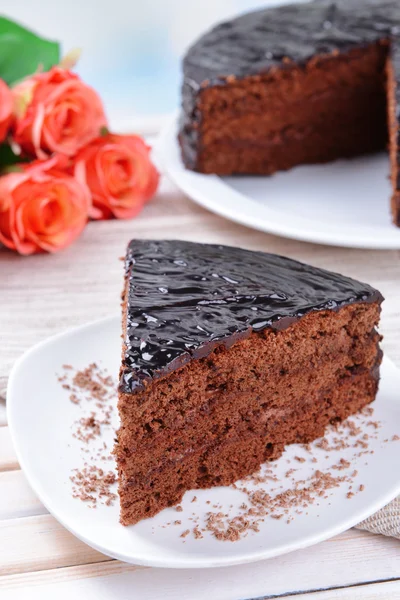 Delicioso bolo de chocolate na placa na mesa no fundo claro — Fotografia de Stock