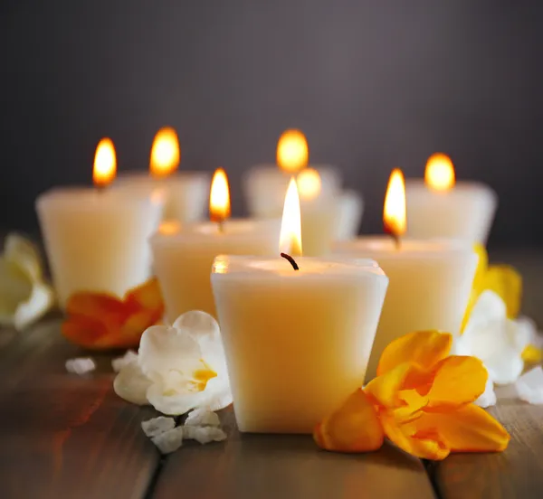 Hermosas velas con flores sobre fondo de madera — Foto de Stock