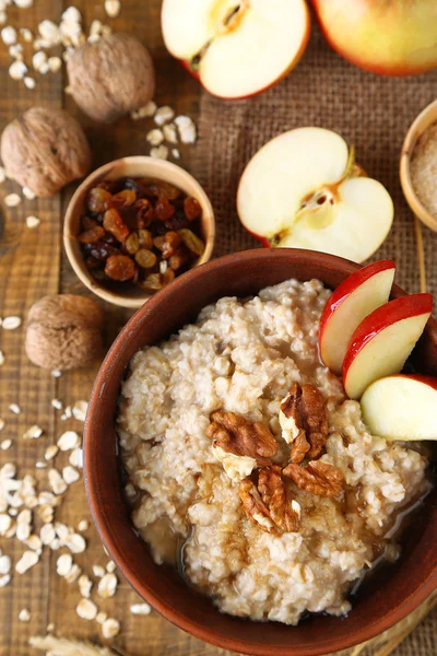 Tasty oatmeal with nuts and apples on wooden table — Stock Photo, Image