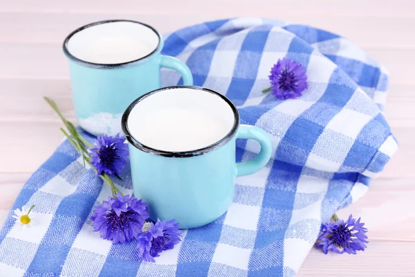 Чашки молока та кукурудзяних квітів на дерев'яному столі — стокове фото