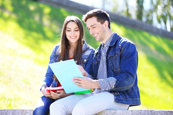 Felices estudiantes sentados en el parque — Stockfoto