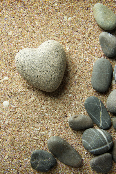 Grey stone in shape of heart, on sand background
