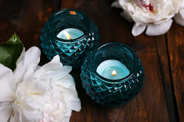 Kerzenständer und Blumen aus Glas auf farbigem Holzhintergrund — Stockfoto
