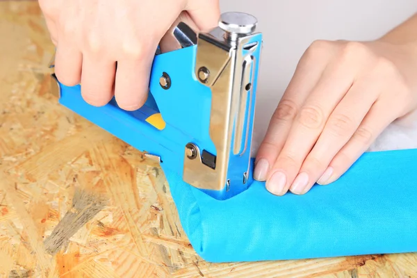 Fastening fabric and board using construction stapler — Stock Photo, Image