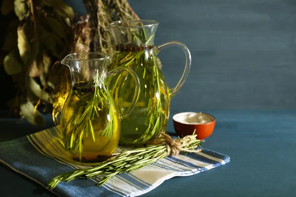 Olio essenziale con rosmarino in brocche di vetro, su fondo di legno — Foto Stock