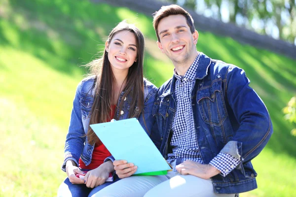 Heureux étudiants assis dans le parc — Photo