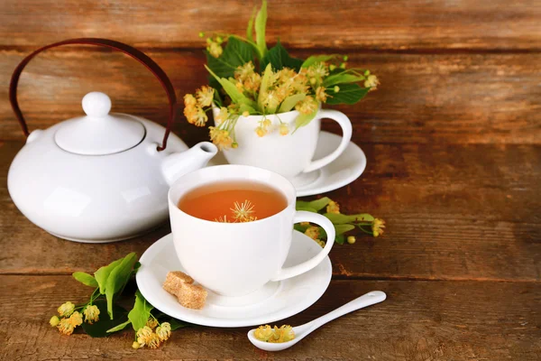 Sabroso té de hierbas con flores de tilo en la mesa de madera —  Fotos de Stock